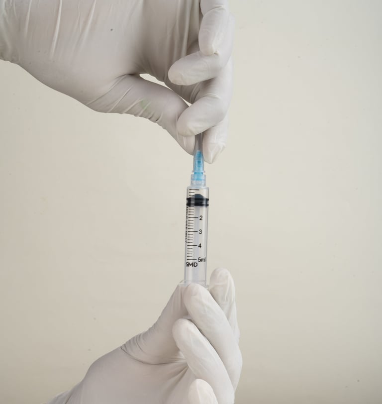 Healthcare worker in white gloves holding a filled syringe with blue needle against neutral background